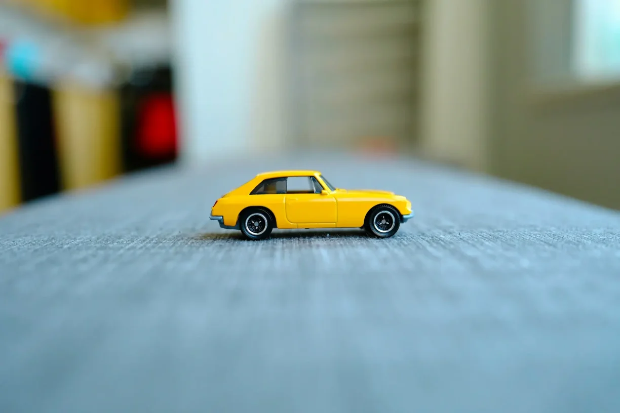 Bright yellow Matchbox MGB GT toy car on a textured grey surface, 247lemonlaw