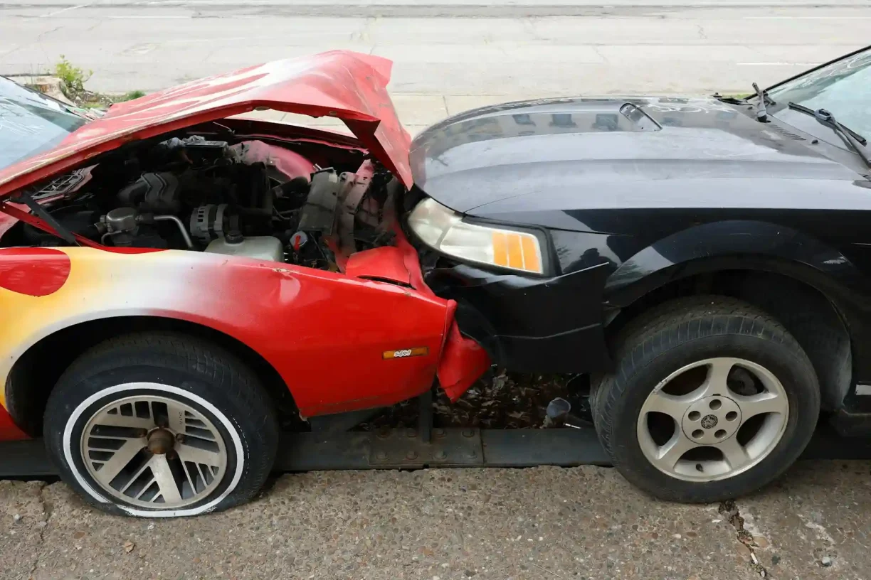 Front-end collision between a red and black car on the street, 247lemonlaw