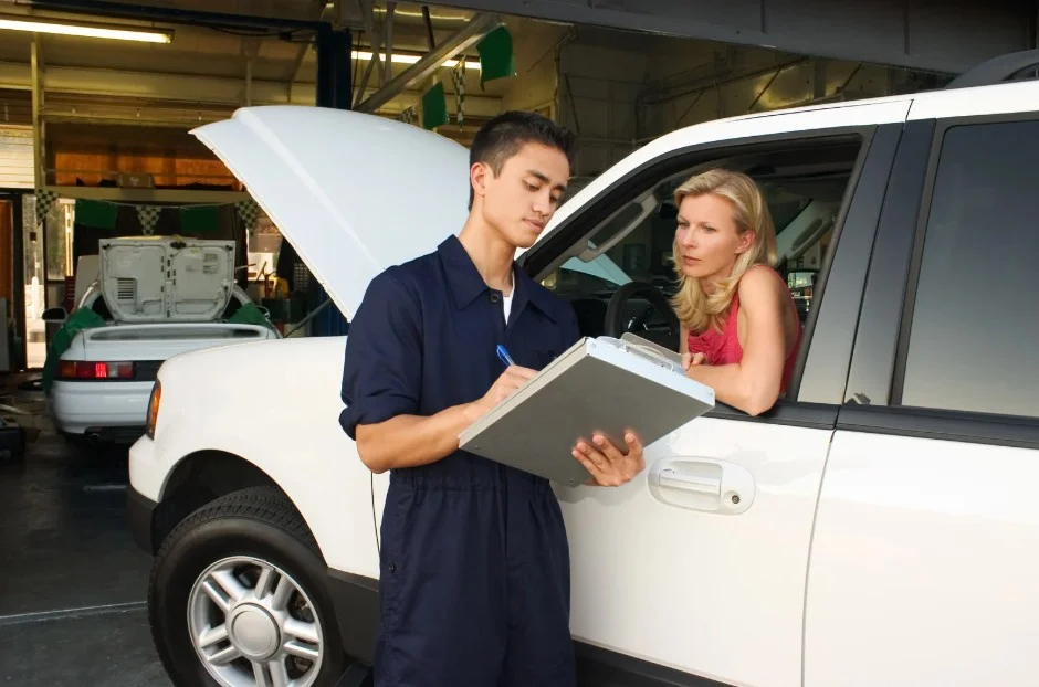 Mechanic explaining repair findings on clipboard to vehicle owner at service shop for 2020 Kia Telluride problems