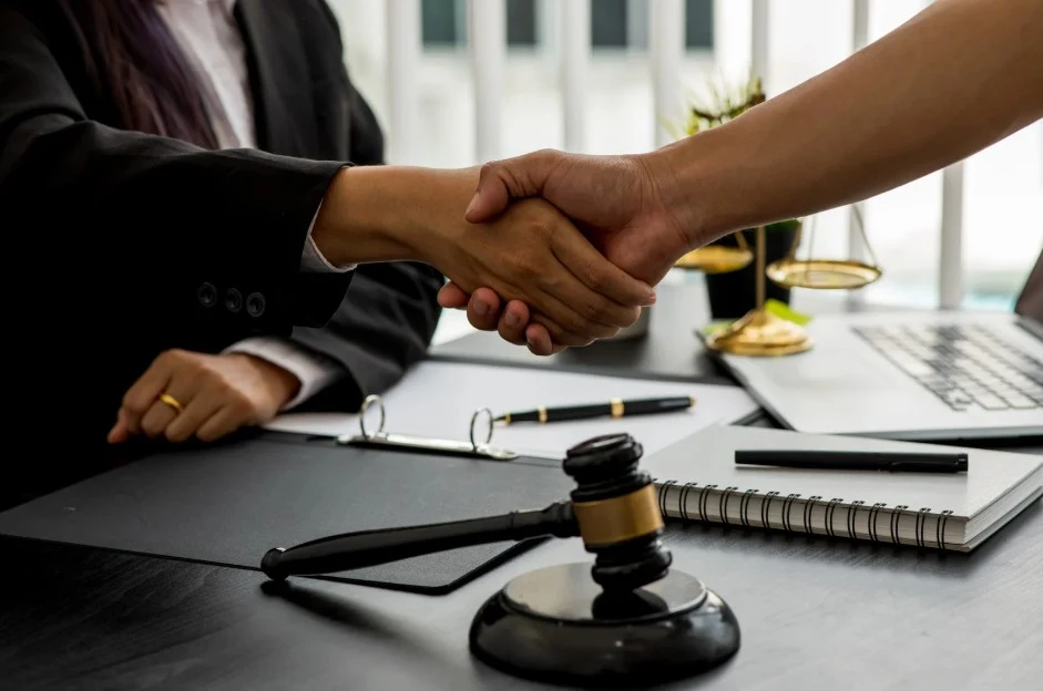 Lemon law attorney shaking hands with client after resolving a claim related to 2020 Kia Telluride problems with gavel on desk