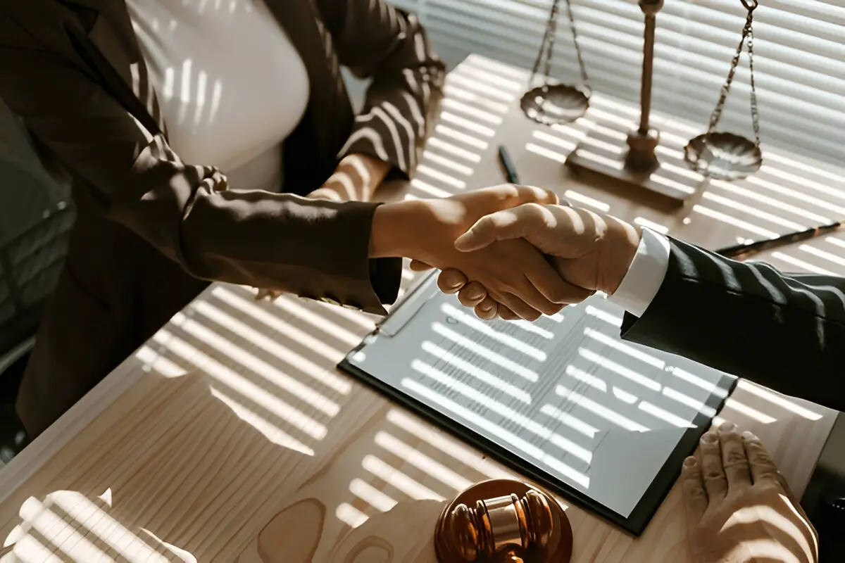 Lemon law attorney shaking hands with client after successful 30 day lemon law Massachusetts claim with justice scales and gavel on desk