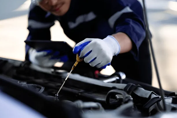 Mechanic inspecting vehicle engine oil level to document defects for Lemon Law claims