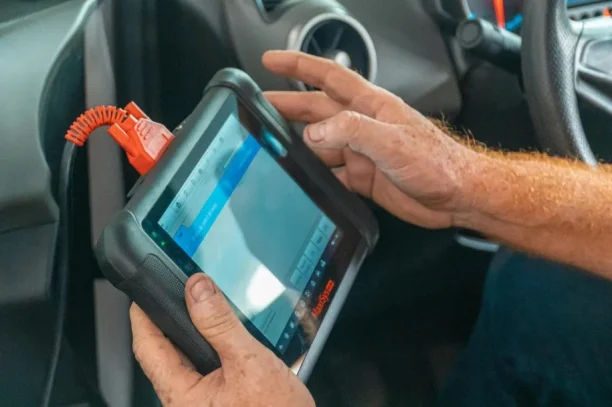 Mechanic using diagnostic scan tool to detect vehicle defects for lemon law case, 247lemonlaw