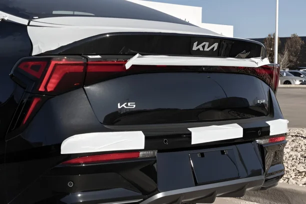 Rear view of a new Kia K5 sedan with protective wrapping, often involved in lemon law disputes