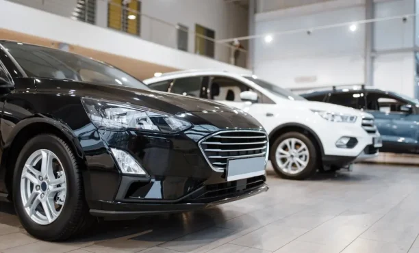Row of new cars displayed inside an auto dealership showroom