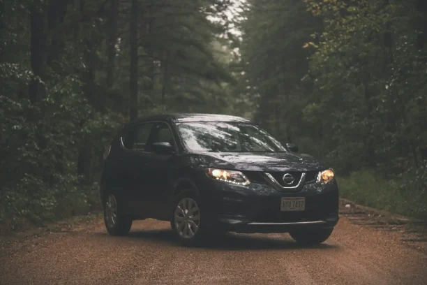 Black Nissan SUV driving on forest road representing lemon law vehicle cases