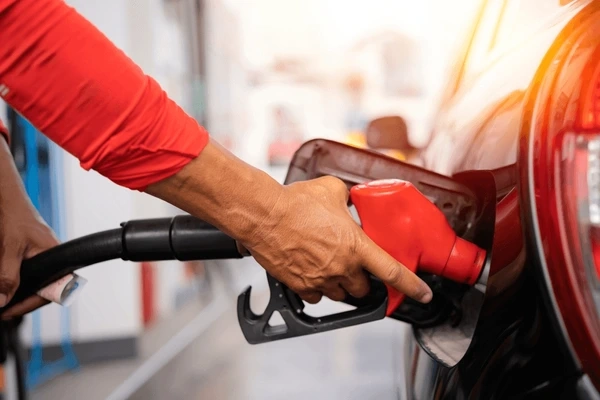 Driver refueling car at gas station highlighting potential lemon law fuel issues