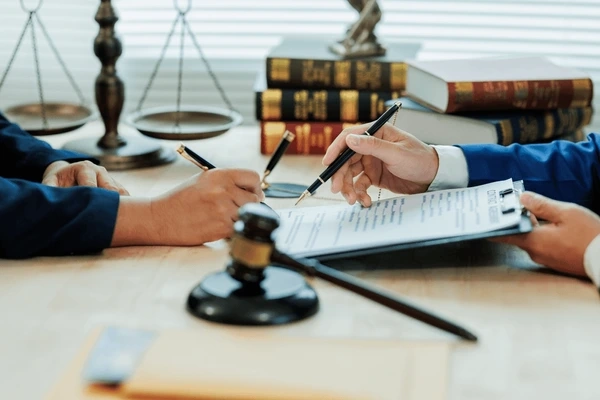 Lawyer and client reviewing lemon law paperwork with gavel and legal books