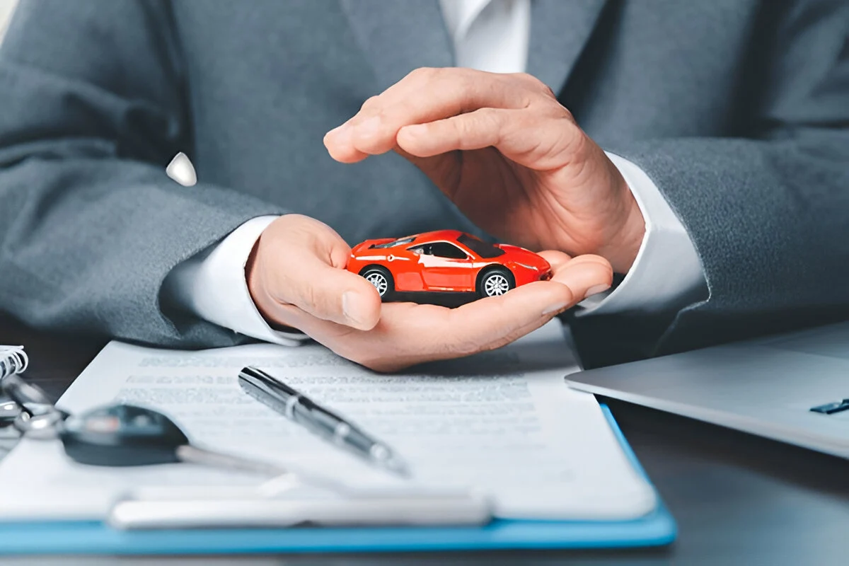 Attorney holding a toy car protectively over paperwork representing legal guidance on what voids a car warranty
