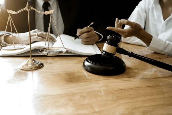 Lemon law attorney consulting with client about filing a claim for 2020 Chevy Colorado problems with gavel and justice scales on desk