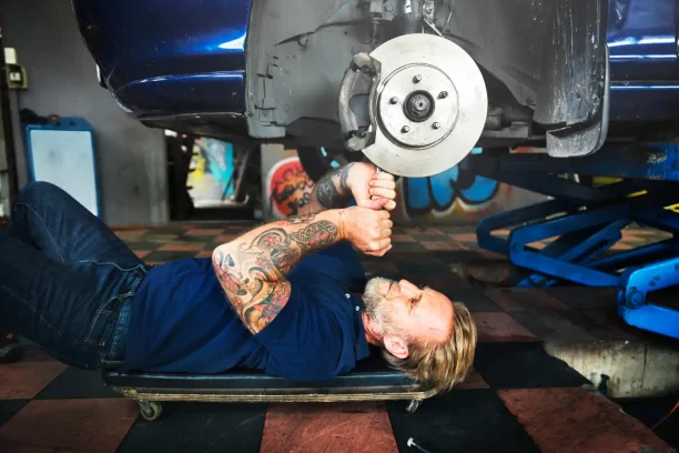 Mechanic repairing vehicle brake system showing potential lemon law issues