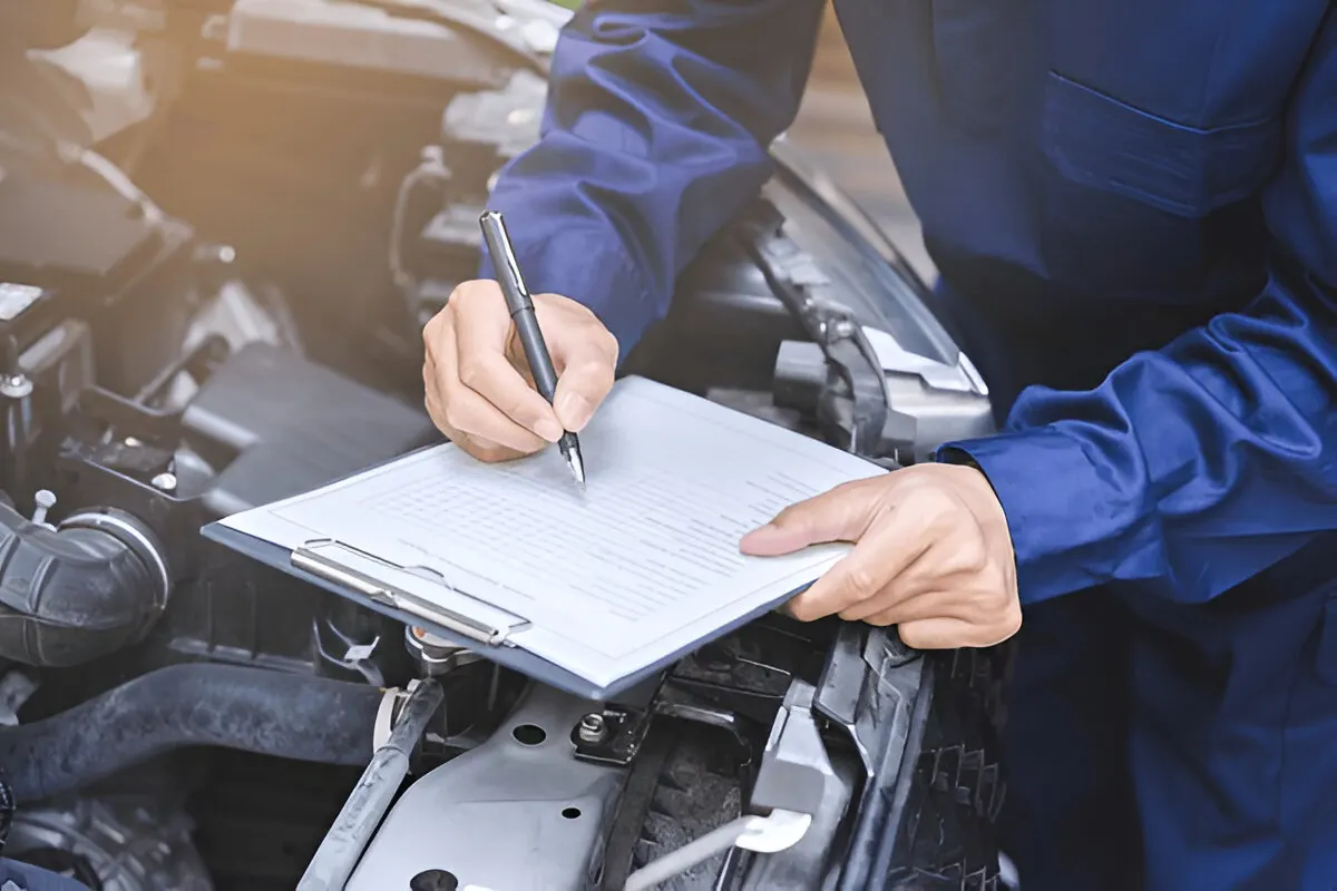 Mechanic documenting vehicle inspection findings on clipboard to determine what voids a car warranty during service