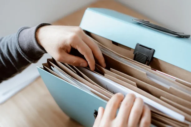 Person organizing car repair documents and warranty files for lemon law claim
