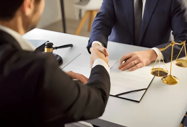 Lawyer and client shaking hands after signing legal agreement in office.