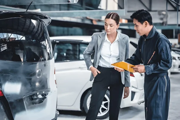 Mechanic discussing car damage report with customer at auto repair shop.