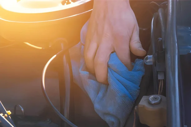 Driver cleaning under the hood while checking for possible engine or fluid related defects that may qualify for Lemon Law help.