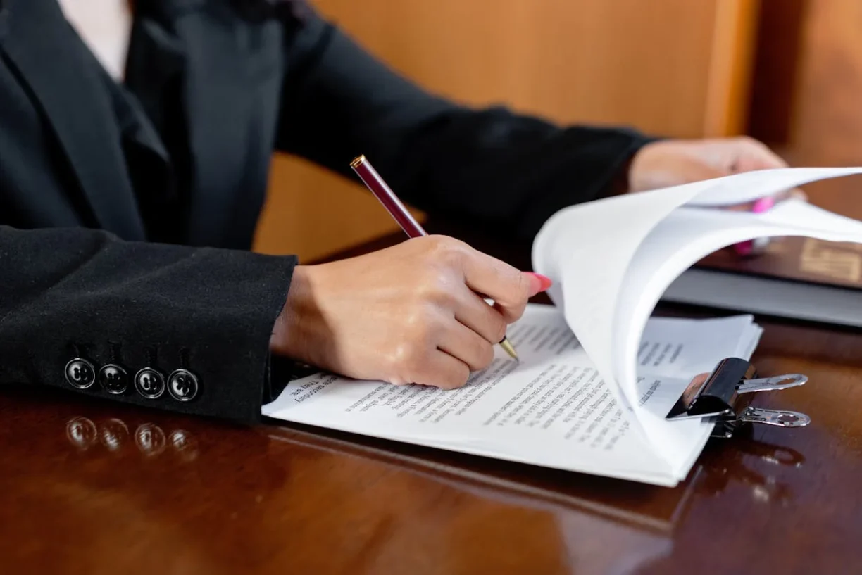 Attorney reviewing and signing legal documents related to a vehicle lemon law case and consumer warranty rights.