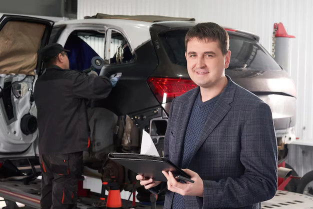Auto body repair inspection with technician working on damaged car panel
