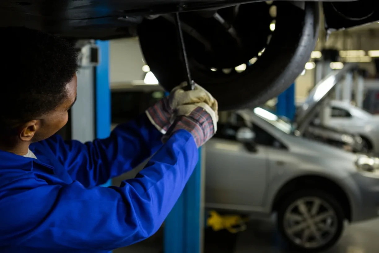 Auto mechanic inspecting and repairing a vehicle on a lift due to repeated mechanical issues that may qualify under lemon law protections.