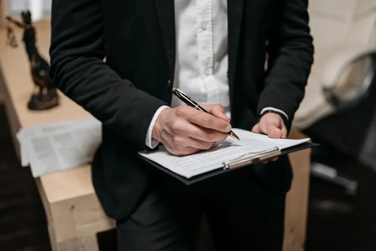 Lawyer reviewing and signing vehicle lemon law claim documents for a car owner