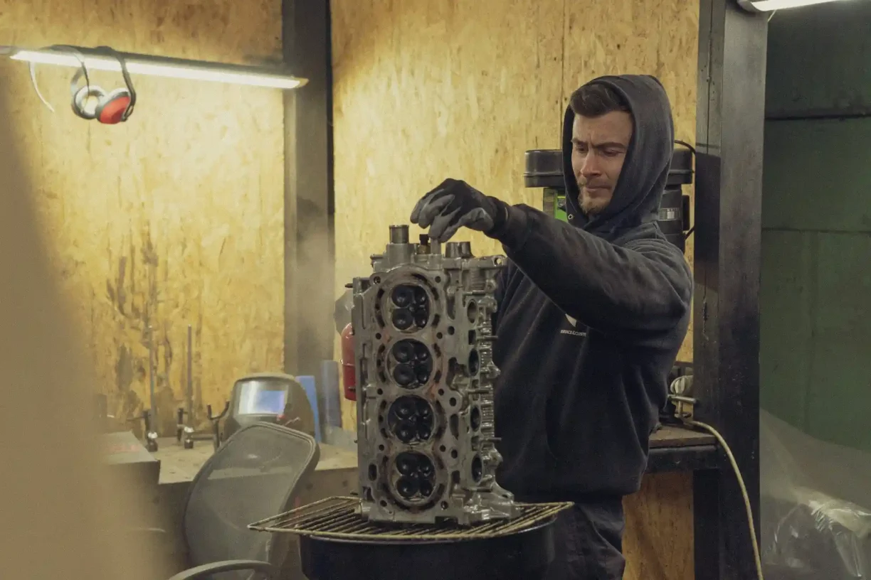 Mechanic handling a faulty cylinder head that may qualify as a lemon vehicle defect