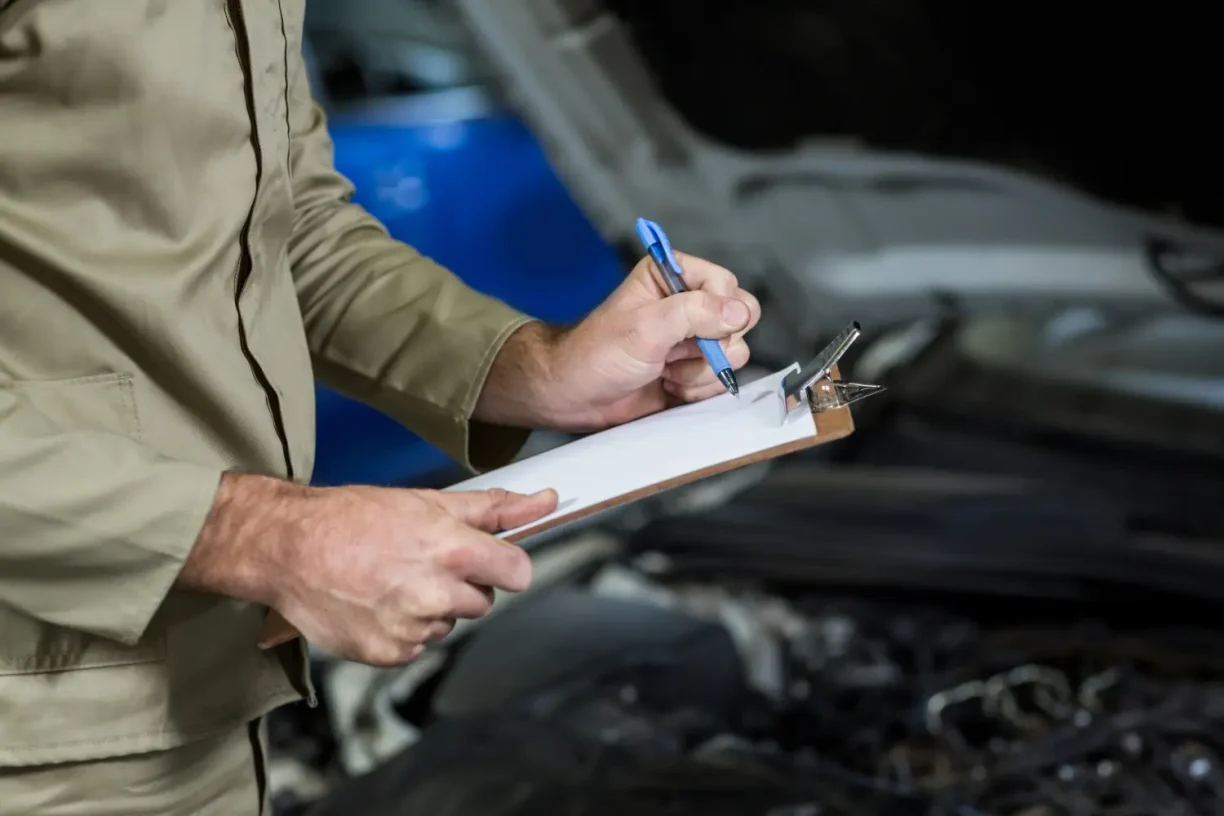 Auto technician documenting repeated repair issues during vehicle inspection